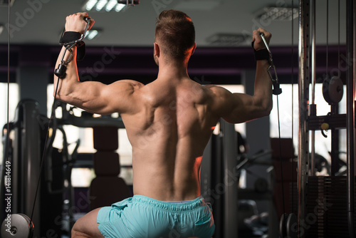 Muscular Man Exercising Shoulders On Machine