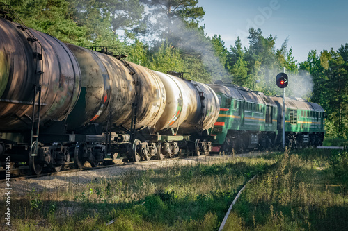 Freight train with tank wagons moving in forest. Green diesel ca