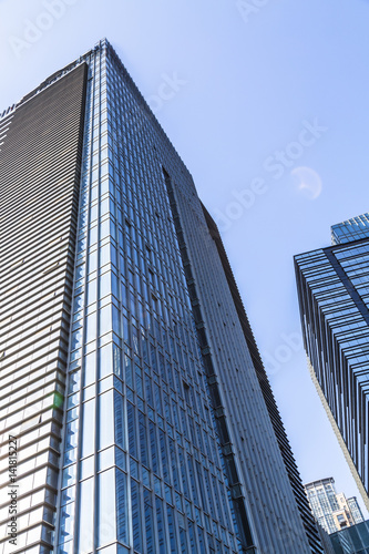 Bottom view of modern skyscrapers in business district against blue sky