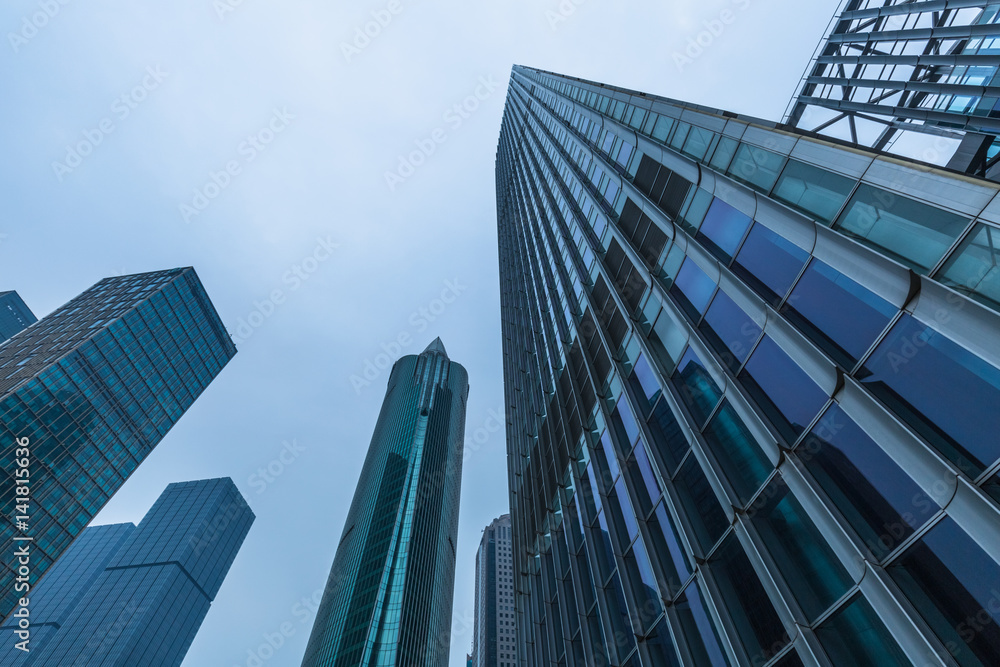 Bottom view of modern skyscrapers in business district against blue sky