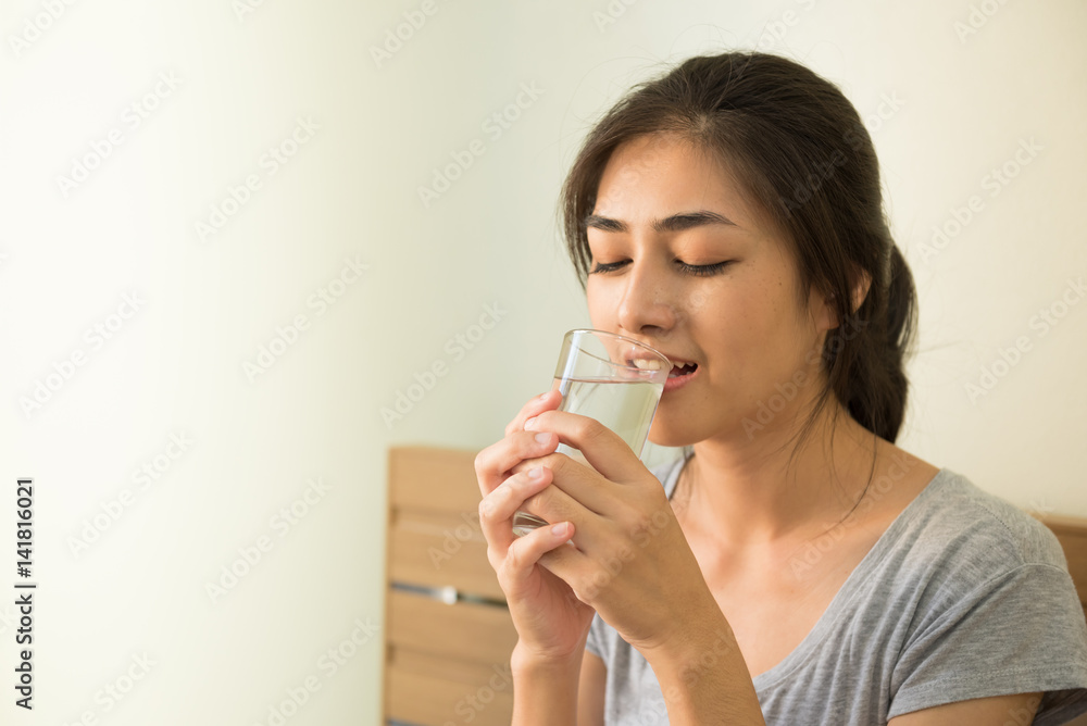 Happy young Asian woman drinking water after waking up ,every thing she does every day in the morning. Happy young Asian woman drinking water after waking up ,every thing she does every day in the morning.