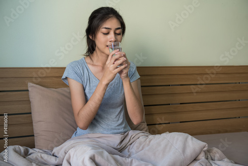 Happy young Asian woman drinking water after waking up ,every thing she does every day in the morning.
