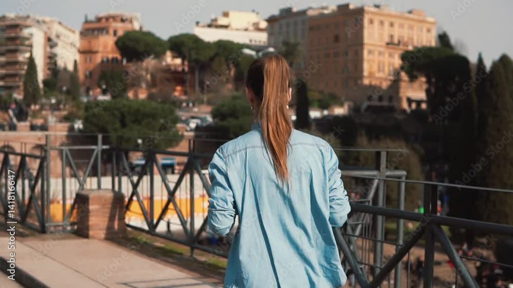 Tourist woman runs down the street in Rome, Italy, takes pictures of Colosseum. Girl looks at the photos. Slow motion.