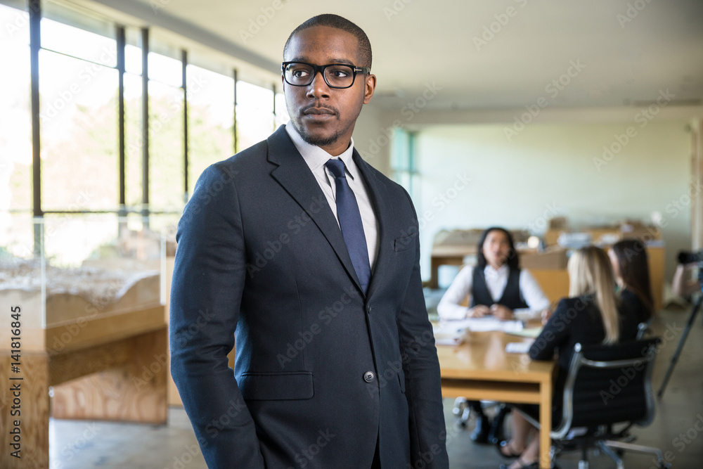 Stylish attractive executive businessman in a suit standing confidently at the workplace office Stylish attractive executive businessman in a suit standing confidently at the workplace office