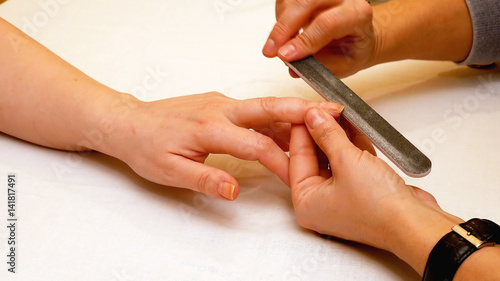 Manicure in the beauty salon. Painting and polishing nails. Spa nails cuticle scarfskin procedure.
