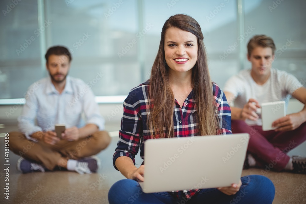 Portrait of female executive sitting on floor and using laptop Portrait of female executive sitting on floor and using laptop