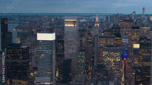 AERIAL NO VISIBLE TRADEMARKS: Iconic Midtown Manhattan skyline lit up against morning sky looking towards downtown financial district. Lights in contemporary skyscrapers turned on and glowing at night