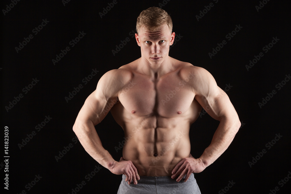 Fototapeta premium Athletic handsome man fitness-model showing six pack abs. isolated on black background with copyspace