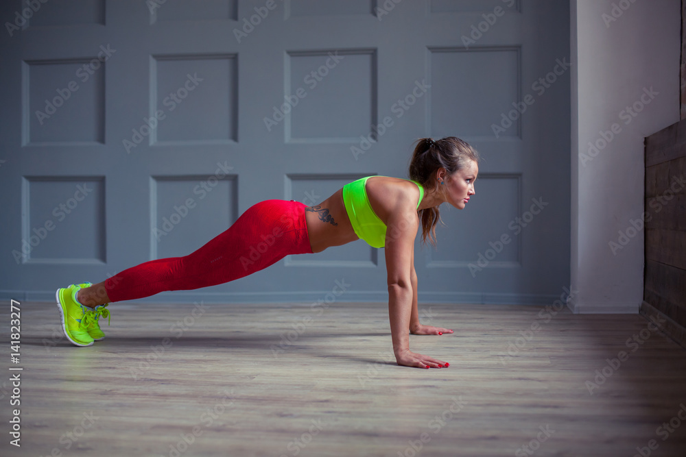 Beautiful fitness woman is doing push-ups in the gym,