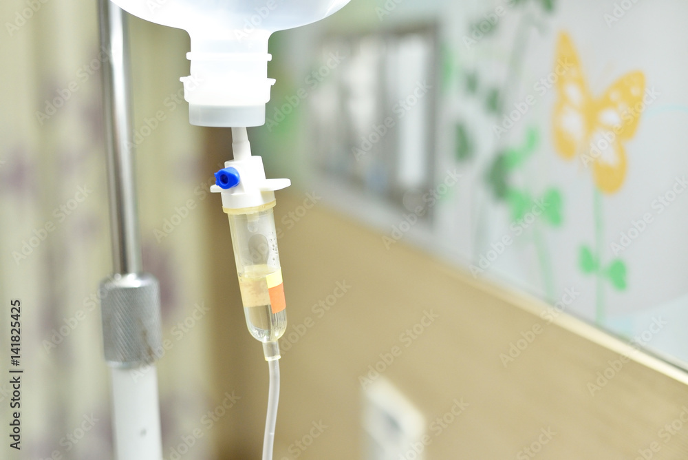Close up saline solution drip for patient and infusion pump in hospital, with copy space wooden wall background at luxury VIP room. Close up saline solution drip for patient and infusion pump in hospital, with copy space wooden wall background at luxury VIP room.