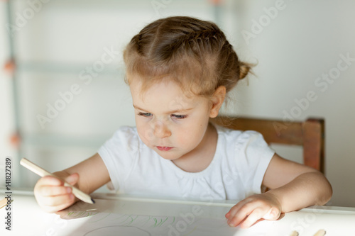 pretty little girl draws with pencils, indoor