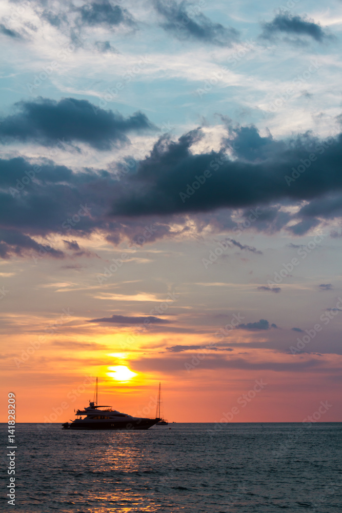 The ship sailing in the sunset. The ship in sunset lights sailing in the ocean. Vertical outdoors shot.