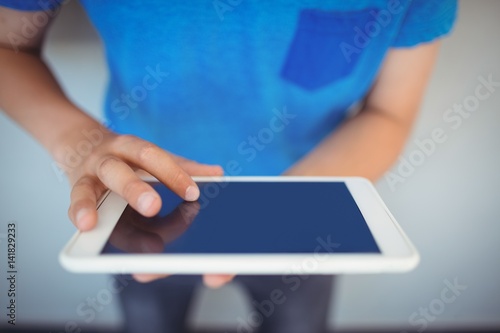 Schoolboy using digital tablet in corridor at school