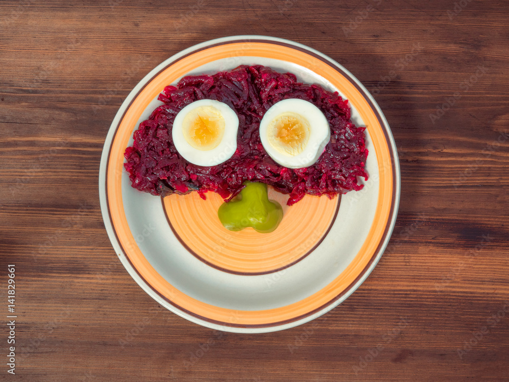 Orange round plate is photographed top view on background of old wood table planks. Ceramic plate with round pattern and beet salad, boiled eggs and slice of sweet pepper, composition of vegetables Orange round plate is photographed top view on background of old wood table planks. Ceramic plate with round pattern and beet salad, boiled eggs and slice of sweet pepper, composition of vegetables