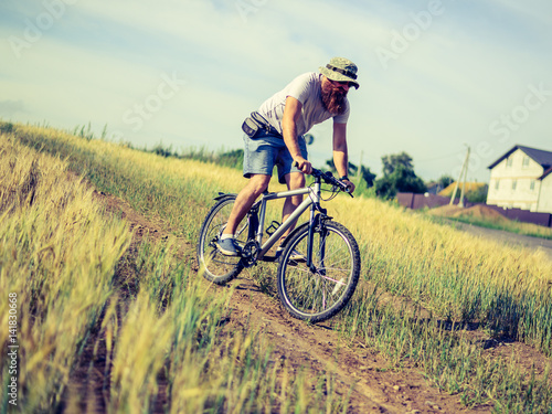 hipster man on a bicycle in the countryside