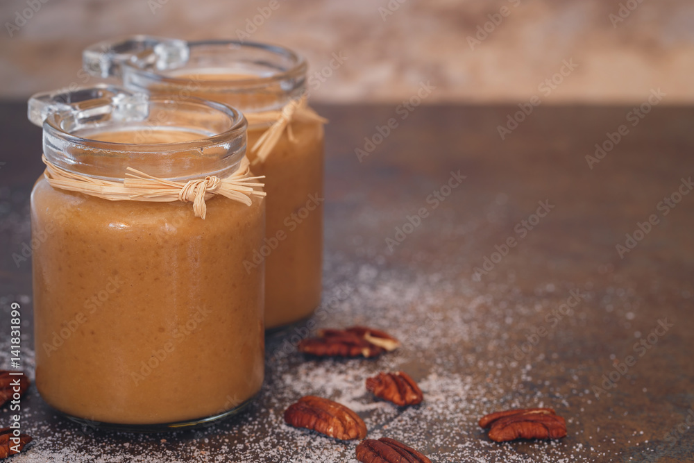 Caramel sauces in a preserving jar with pecan nuts next to it Caramel sauces in a preserving jar with pecan nuts next to it