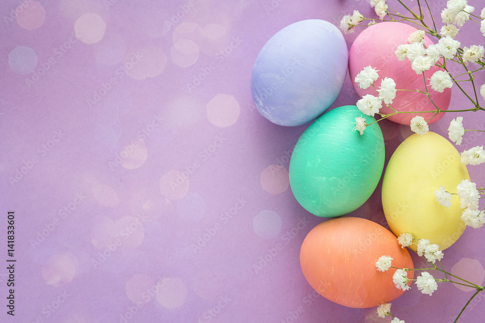 Easter eggs and white flowers on purple background. Space for text. Easter eggs and white flowers on purple background. Space for text.