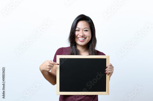 Smiling woman pointing to a blank blackboard