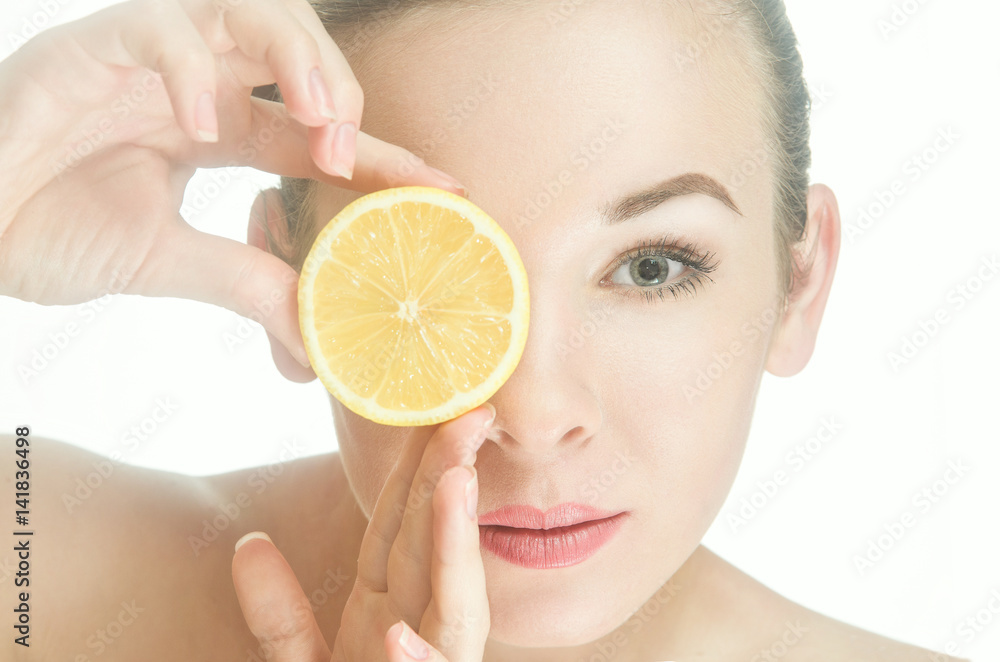 beauty woman looks at the photographer through a slice of lemon beauty woman looks at the photographer through a slice of lemon