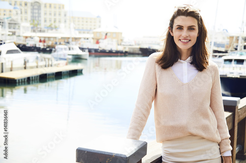 Beautiful brunette standing at harbor, portrait