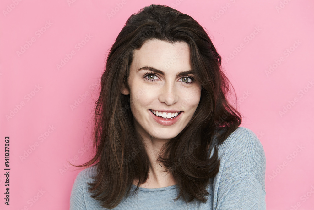 Brunette woman smiling against pink background Brunette woman smiling against pink background