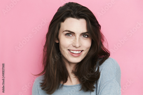 Brunette woman smiling against pink background
