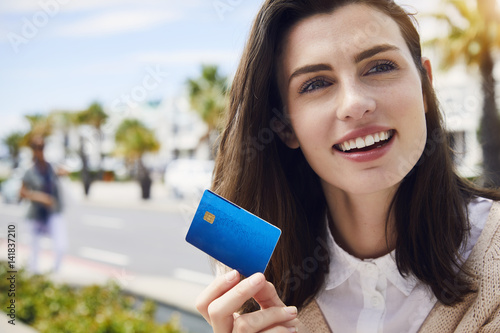 Beautiful woman holding credit card, looking away