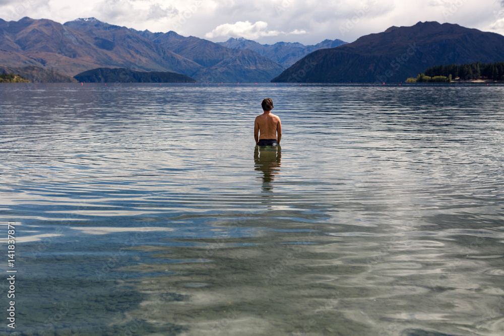 Man standing in still remote lake

