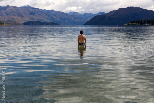 Man standing in still remote lake 