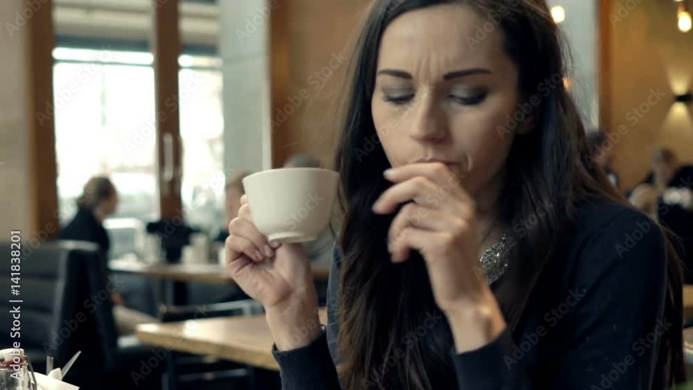 Pensive, sad woman drinking coffee by table sitting in cafe
Pensive, sad woman drinking coffee by table sitting in cafe