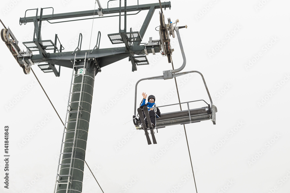 Skier wearing skiing outfit going to the mountain's pike by ski lift Skier wearing skiing outfit going to the mountain's pike by ski lift