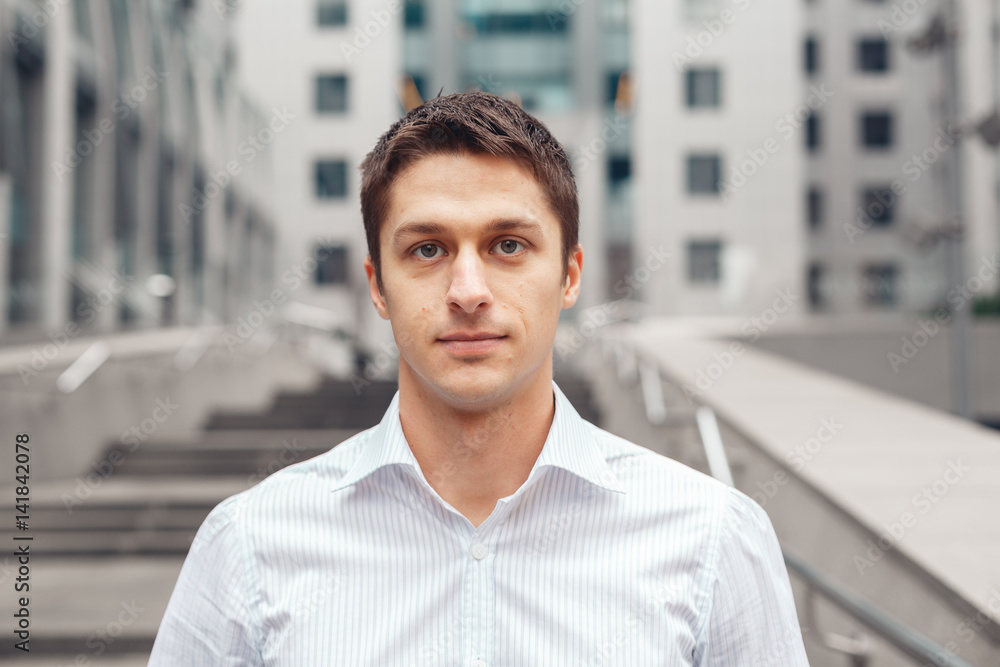 Portrait of an handsome businessman against the background of the business center. Young man in an urban setting. Portrait of an handsome businessman against the background of the business center. Young man in an urban setting.