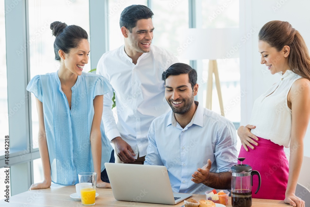 Smiling business colleagues discussing over laptop Smiling business colleagues discussing over laptop
