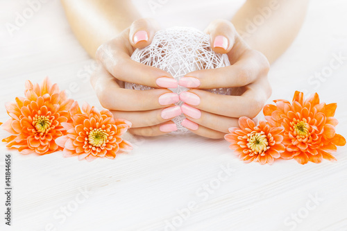 pink manicure with orange chrysanthemum flowers. spa