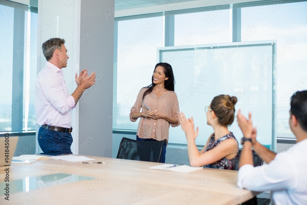 colleagues clapping for businesswoman in conference room