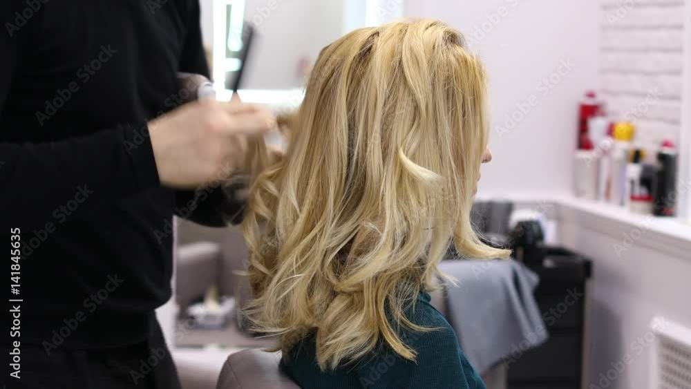 Styling hair in the beauty salon. Calm beautiful blonde woman in a hairdresser Styling hair in the beauty salon. Calm beautiful blonde woman in a hairdresser