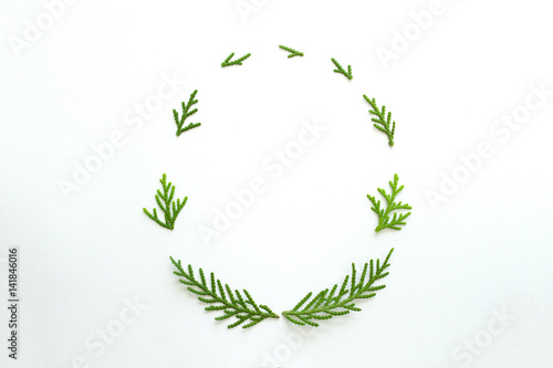 Oval frame of fir branches on white background. Flat lay, top view.