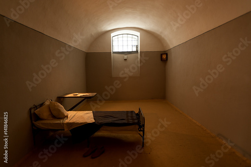 Dark prison cell with antique furniture inside historical fortress
