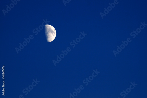 mezza luna lucente nel cielo blu della sera photo