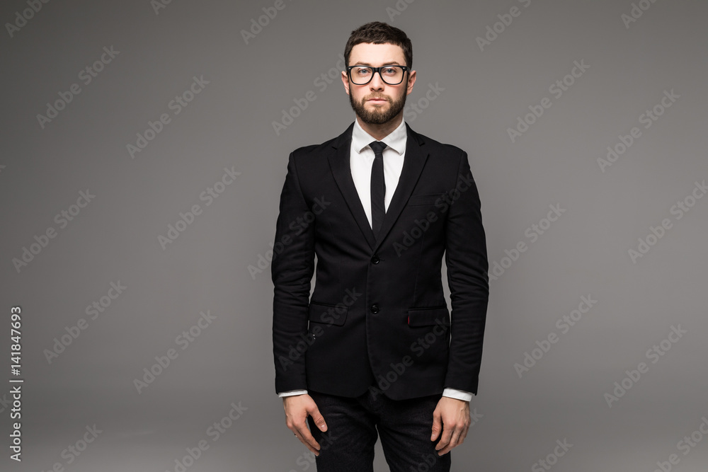 Fototapeta premium Handsome young bearded businessman in classic suit and looking away, on a gray background