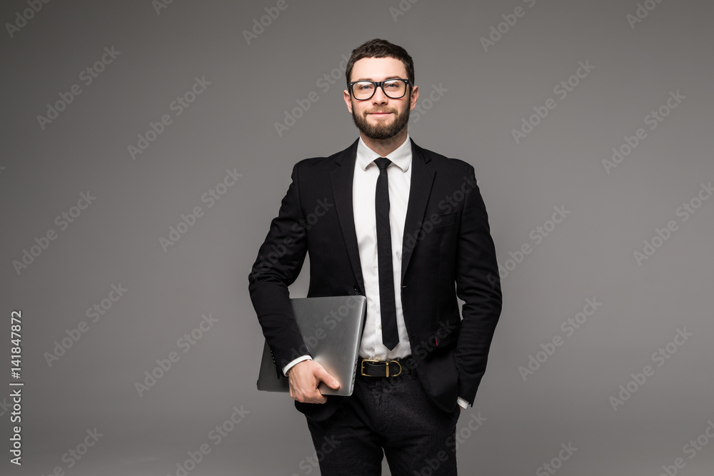 Handsome business man in glasses and suit holding laptop in hands side view isolated gray background Handsome business man in glasses and suit holding laptop in hands side view isolated gray background