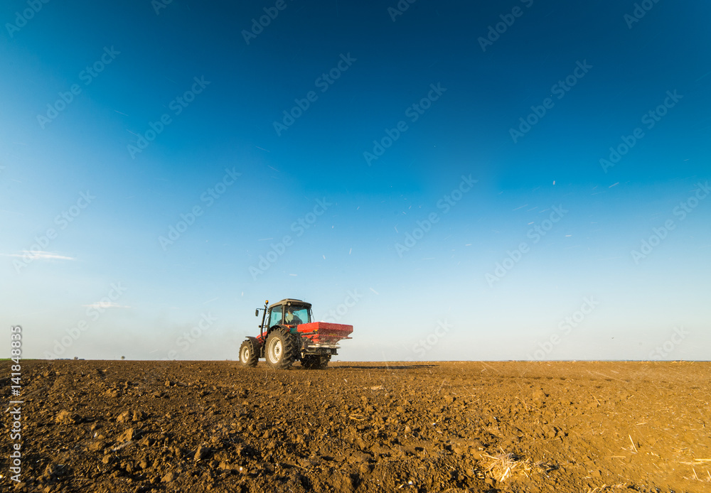 Fototapeta premium Tractor spreading artificial fertilizers