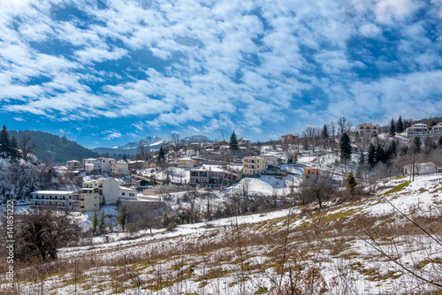 Mountainous snowy village under cloudscape on Plastira lake in central Greece