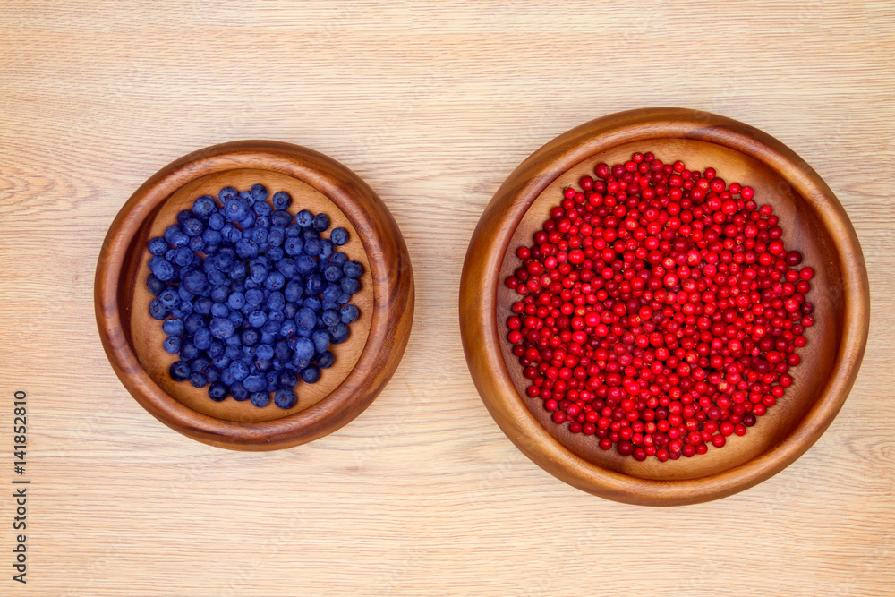 Healthy food. Wooden plates with fresh wild strawberries and blueberries isolated on beige background. Healthy food. Wooden plates with fresh wild strawberries and blueberries isolated on beige background.