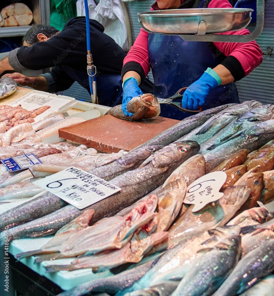 woman preparing a fresh fish at a fish stall at Atarazanas market in Malaga