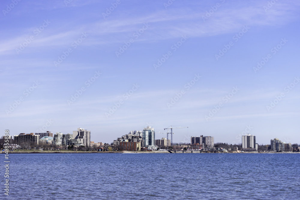 Low urban skyline across a blue water, large sky, background space for text