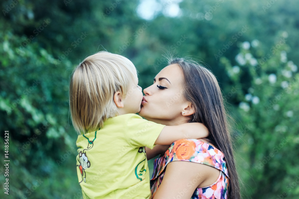 Cute little child kissing and hugging pretty mother Cute little child kissing and hugging pretty mother
