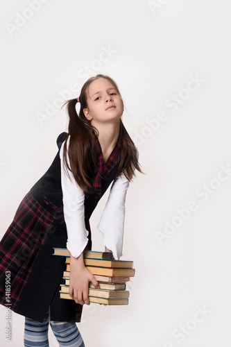 A girl in school uniform holds a lot of books photo