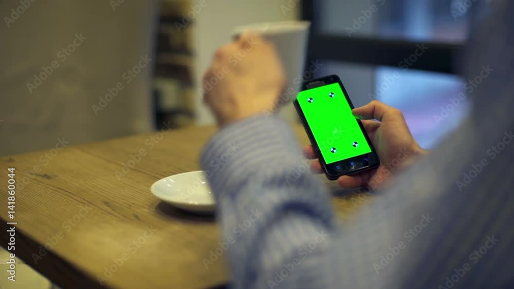 Man is Holding Smartphone with Green Screen in cafe Man is Holding Smartphone with Green Screen in cafe