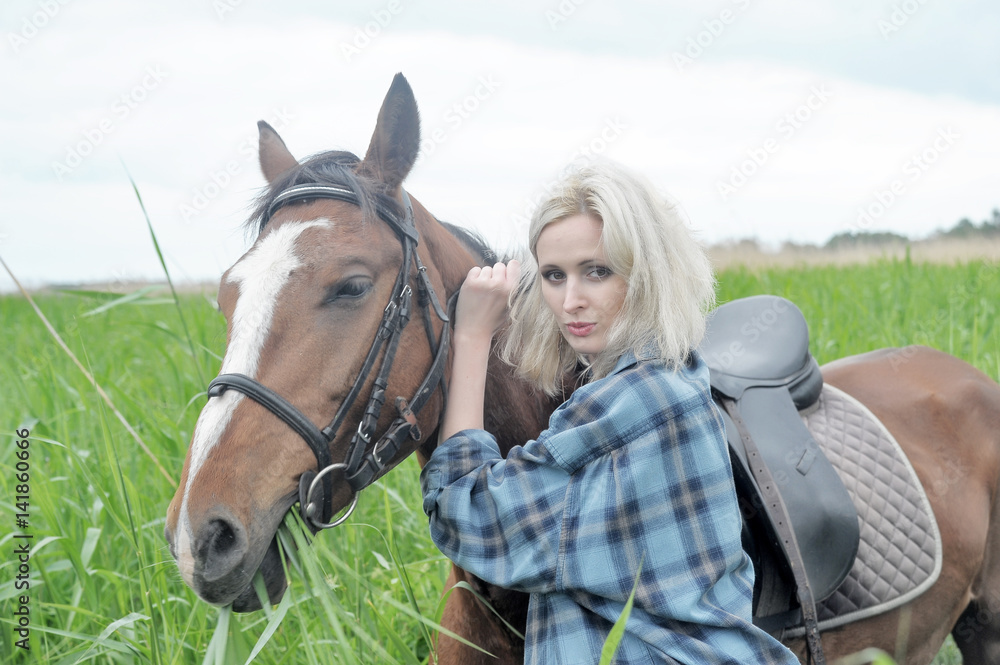 Obraz premium Blonde in a field with a brown horse